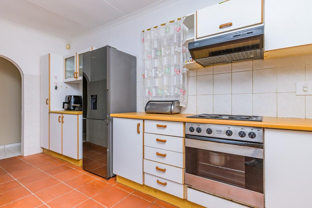A functional kitchen featuring built-in cabinetry, a gas hob with extractor fan, built-in oven, and tiled flooring.