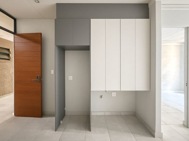 A clean and modern laundry area featuring built-in cabinetry, tiled flooring, and dedicated plumbing and electrical connections for appliances.
