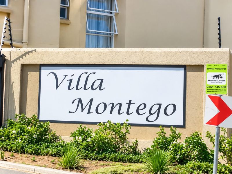 Entrance signage for Villa Montego townhouse complex featuring a rendered boundary wall with integrated electric security fencing.