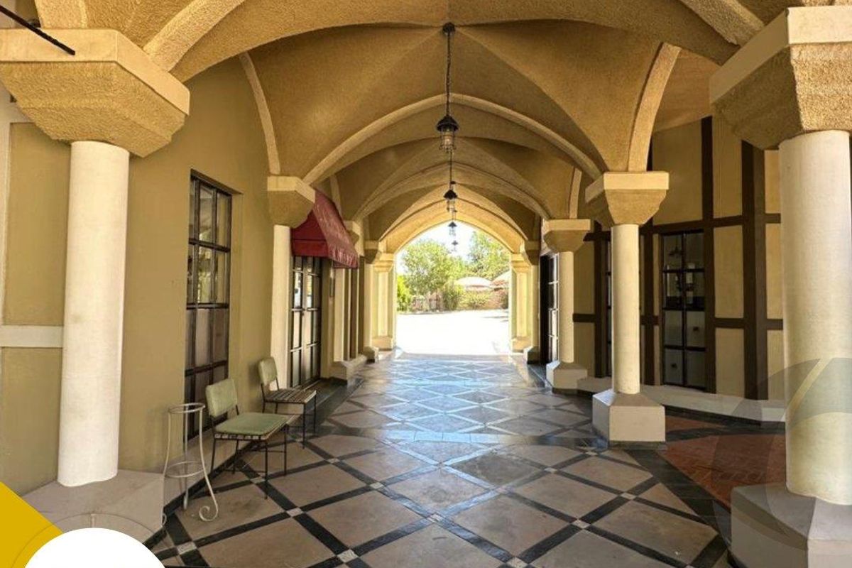 A covered outdoor walkway featuring elegant vaulted ceilings, stone columns, and decorative tiled flooring, providing a sophisticated architectural transition space.
