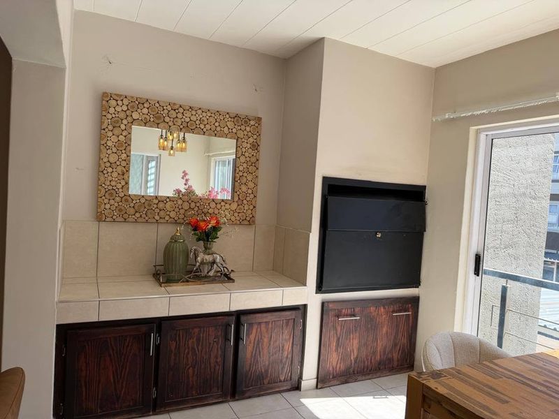 Living area featuring a built-in fireplace, tiled counter space with wooden cabinetry, and access to a balcony through a sliding glass door.