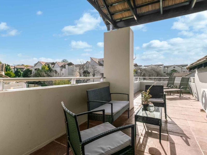Spacious covered balcony featuring tiled flooring, a metal balustrade, and an exposed timber roof structure, offering an ideal outdoor relaxation area.