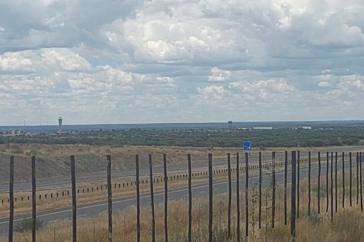 A wide-angle view of the agricultural land featuring perimeter fencing with a highway and distant landscape in the background.