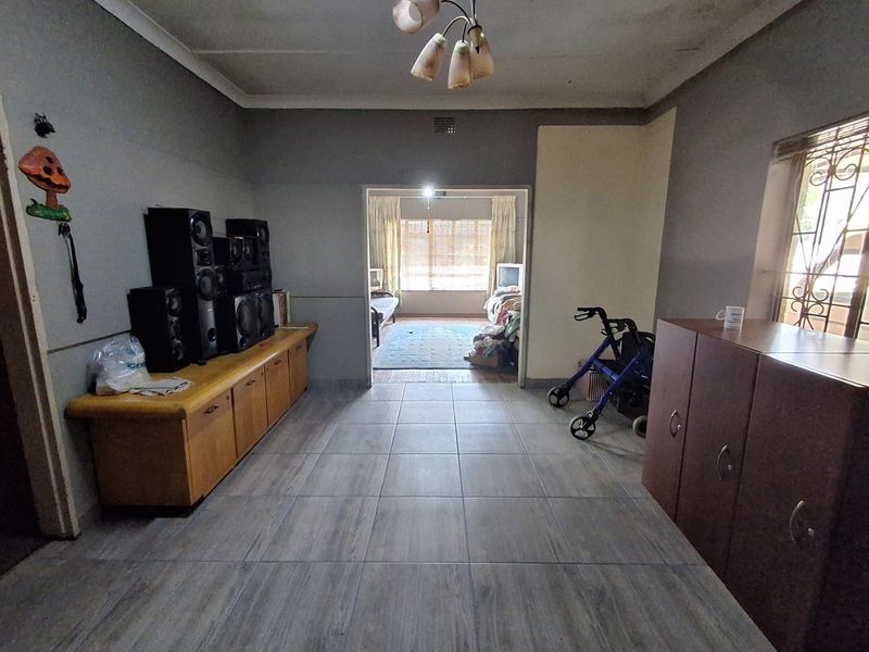A living area featuring tiled flooring and a ceiling light fixture, with an open transition to an adjacent room.