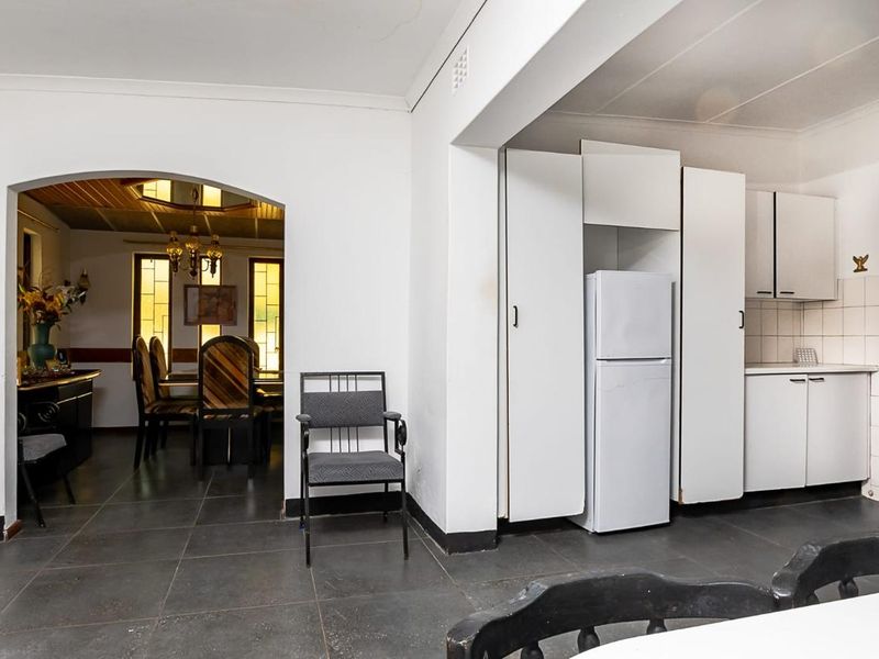 Open plan kitchen and dining area featuring tiled flooring, built-in cabinetry, and a classic arched entryway connecting the spaces.