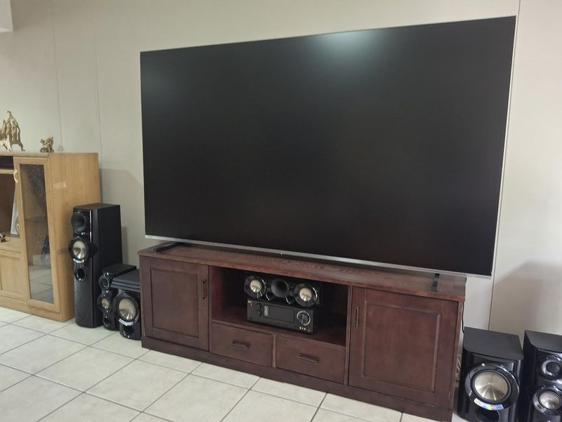 A living room area featuring neutral wall tones and tiled flooring, currently set up as a home entertainment space.