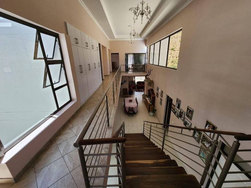 Spacious upper-level hallway featuring a wooden staircase with metal balustrades, built-in storage cabinetry, and views overlooking the lower living area.