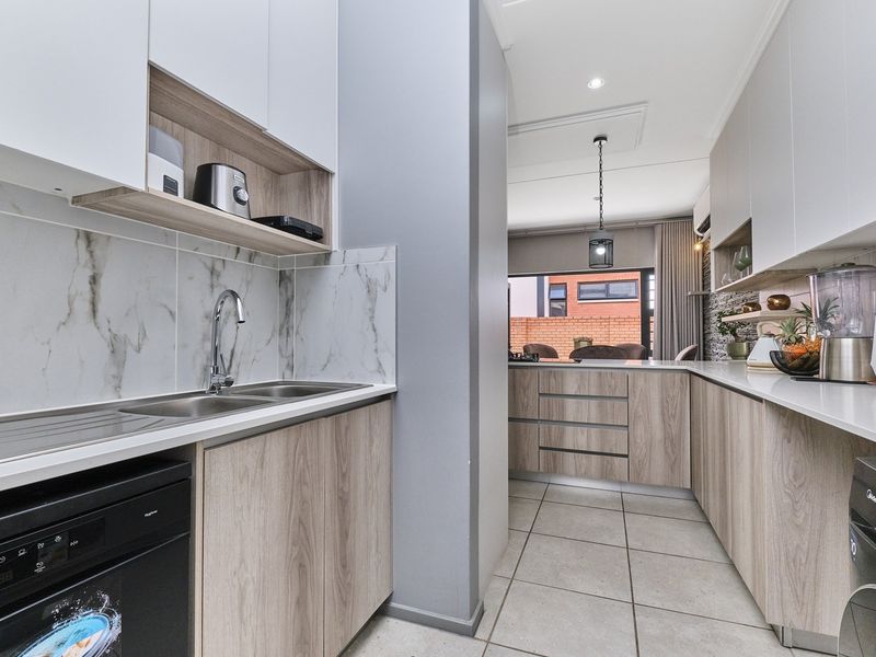 Modern kitchen featuring sleek wood-grain cabinetry, marble-look splashbacks, stone countertops, and high-quality finishes, seamlessly flowing into the adjacent living area.