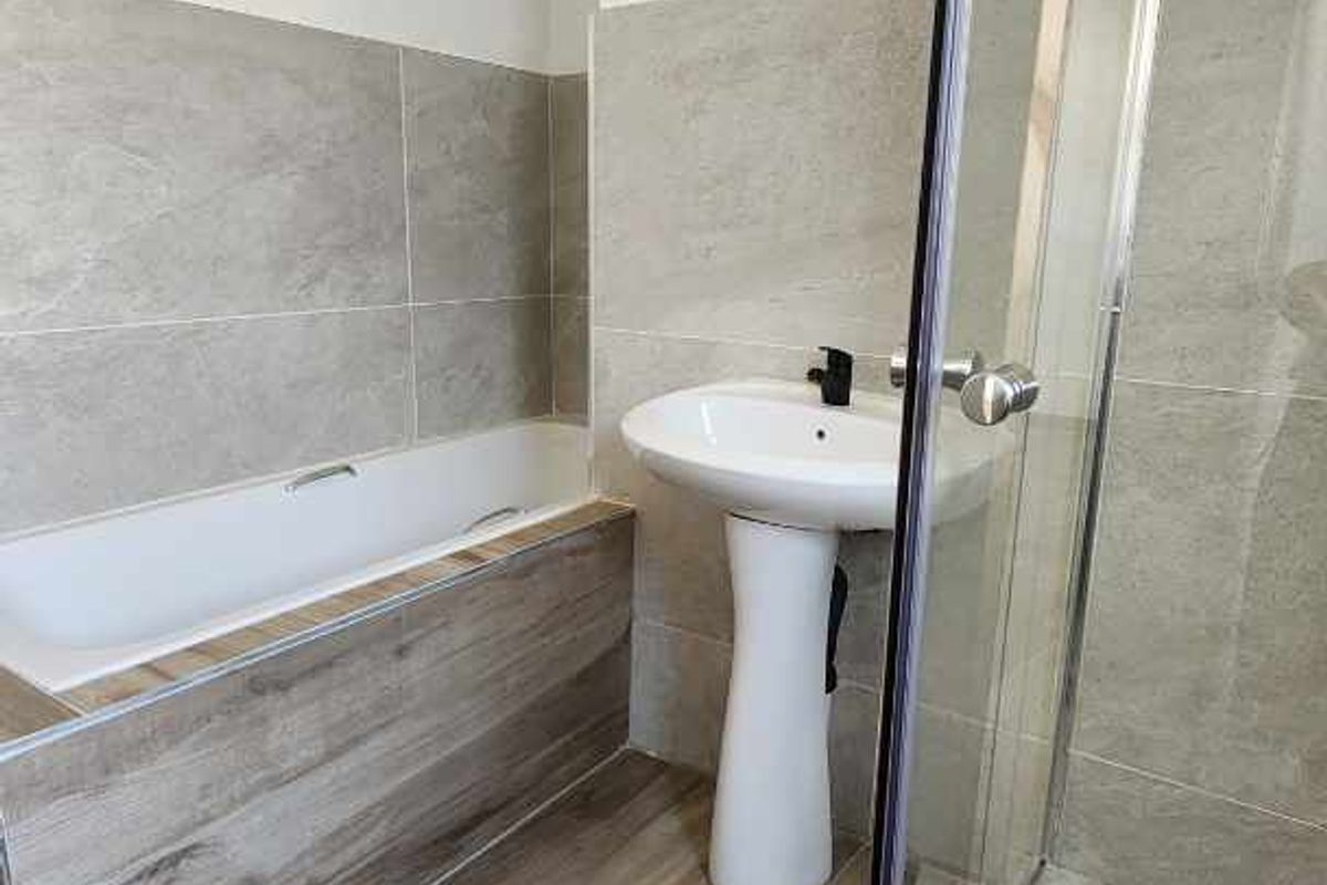 Modern bathroom featuring a tiled bathtub, pedestal sink, and a separate glass-enclosed shower with mosaic floor detailing.