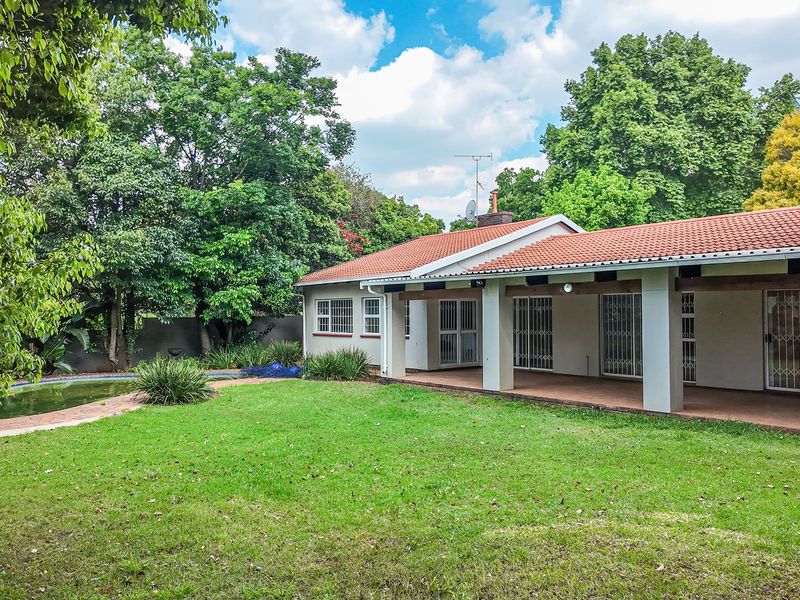 Rear view of the property featuring a covered patio, swimming pool, and a spacious garden area.