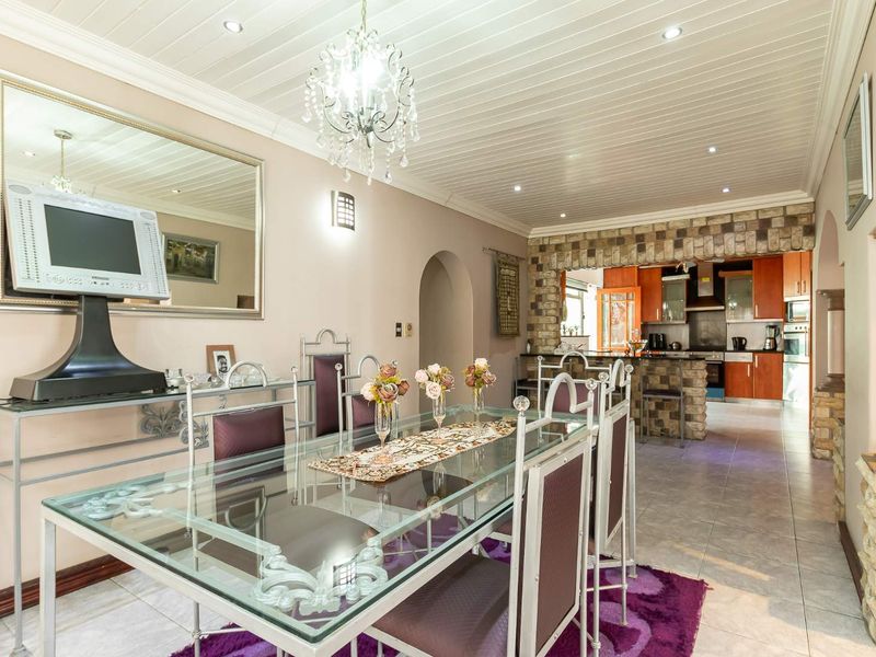 Open plan dining area flowing into a kitchen featuring a stone breakfast bar, tiled flooring, and a distinctive tongue and groove ceiling.