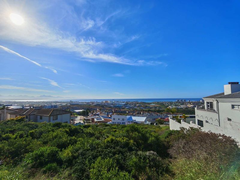 A scenic elevated view overlooking a coastal residential neighbourhood and the distant ocean horizon.