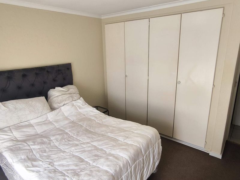 A bedroom featuring built-in cupboards and carpeted flooring, providing functional storage space.