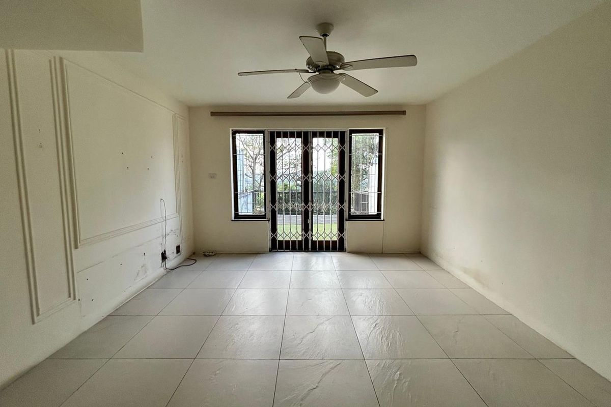 An empty living room featuring large format floor tiles, a ceiling fan, and security gates leading to an outdoor area.