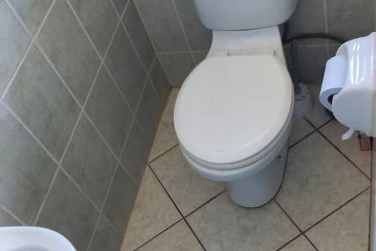 A compact bathroom featuring tiled walls and flooring, equipped with a standard toilet and a small basin.