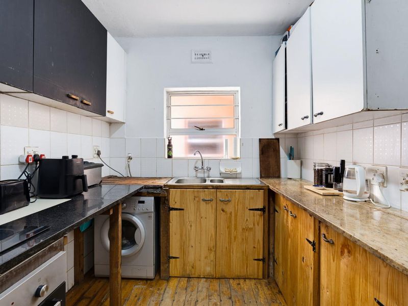 A functional kitchen featuring a double sink, built-in cabinetry, tiled backsplash, and integrated oven, offering potential for modernization and aesthetic updates.