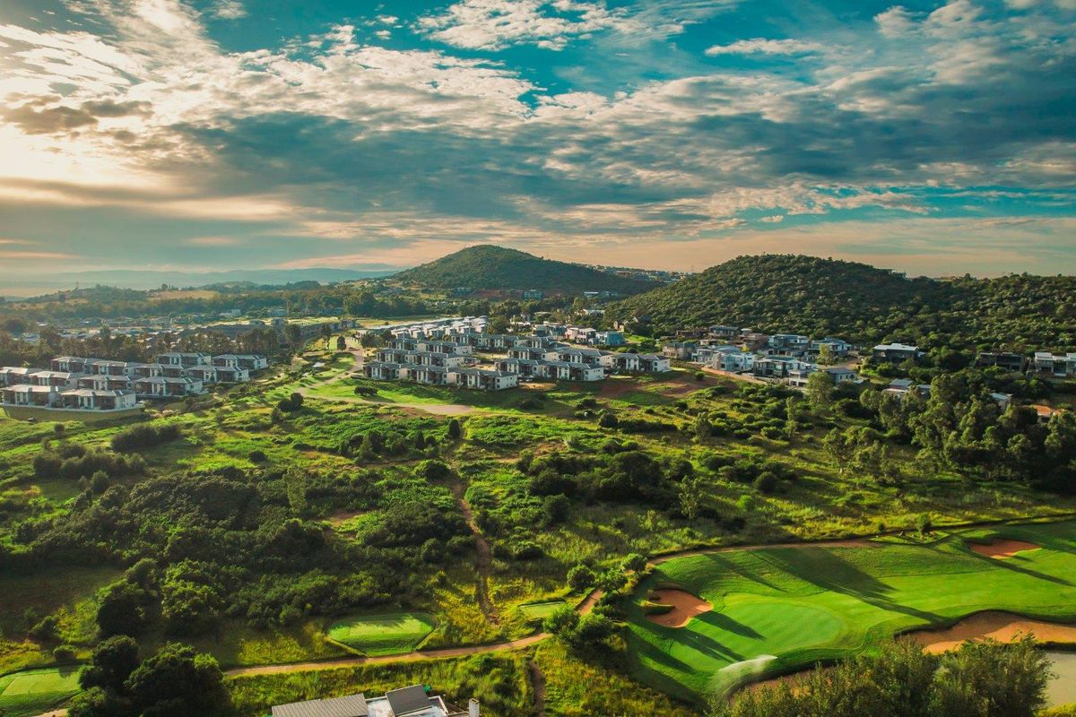 An aerial view of a residential estate integrated with a golf course, showcasing the surrounding landscape and hilly terrain.