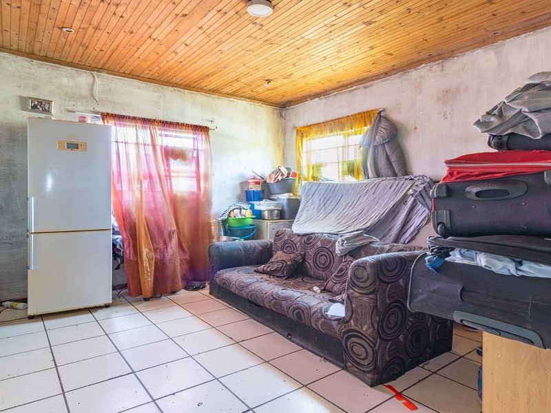 A living area featuring tiled flooring and a timber ceiling, currently requiring significant cosmetic updates and wall repairs to improve its overall condition.