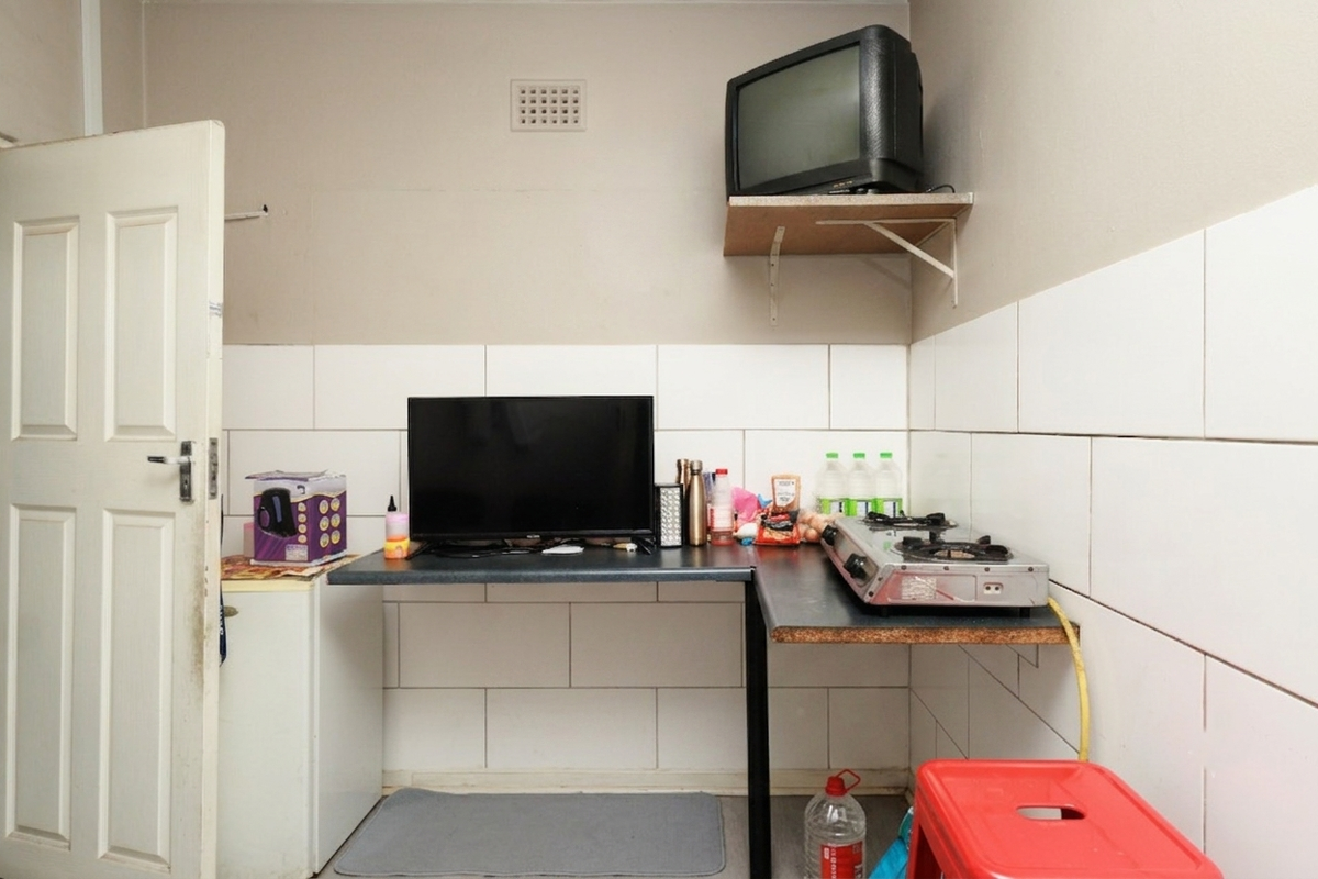A compact kitchen area featuring tiled walls, a built-in countertop workspace, and a gas hob setup.