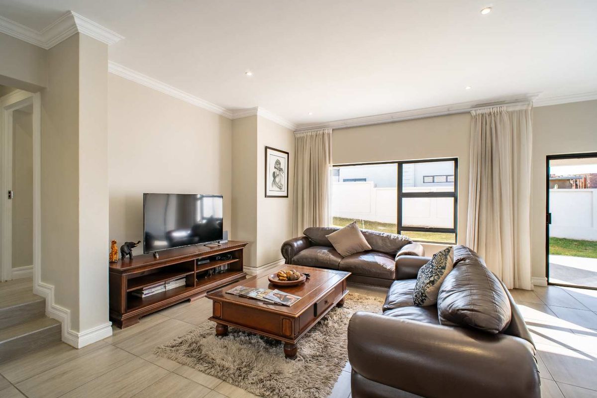 A bright and spacious living room featuring large windows, tiled flooring, and recessed ceiling lighting, offering a comfortable and well-maintained living space.