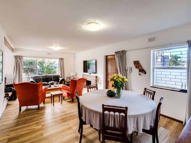 Spacious open-plan living and dining area featuring laminate flooring, a fireplace, and large windows with security bars.