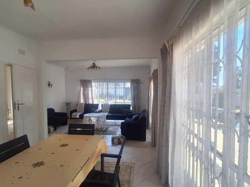 Spacious open-plan living and dining area featuring tiled flooring, large sliding doors with security gates, and natural light.