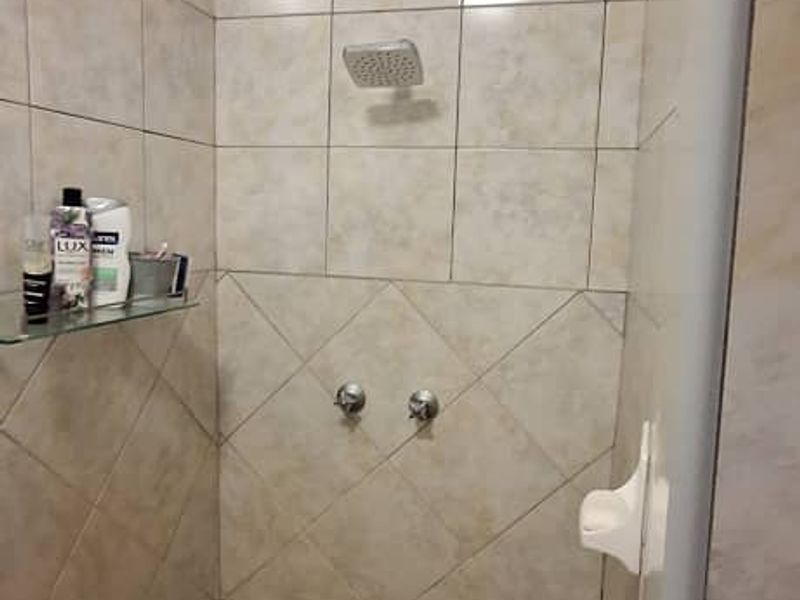 A functional shower enclosure featuring neutral wall tiling, a brick-patterned floor, and integrated shower fixtures.