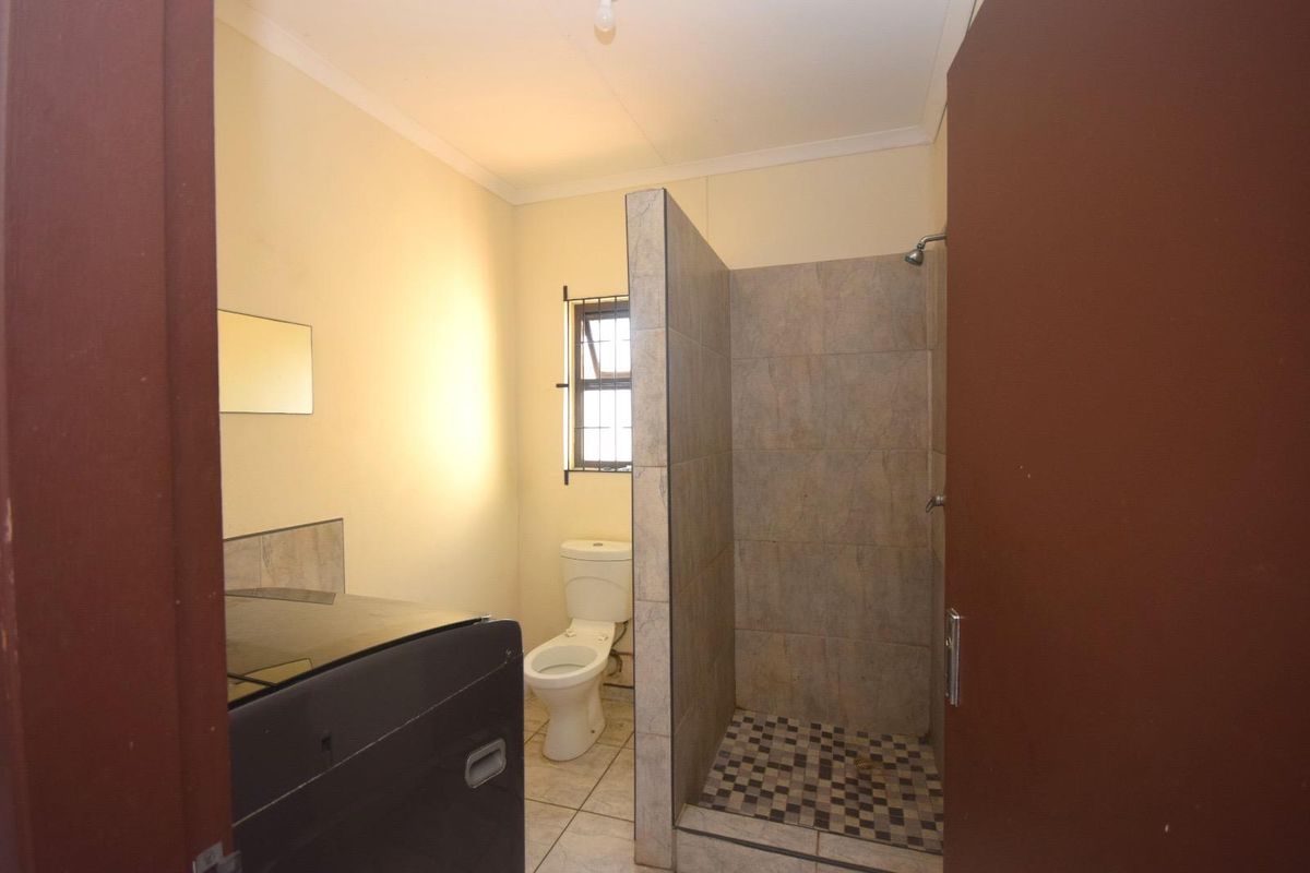 A functional bathroom featuring a walk-in shower with tiled enclosure, a standard toilet, and tiled flooring.