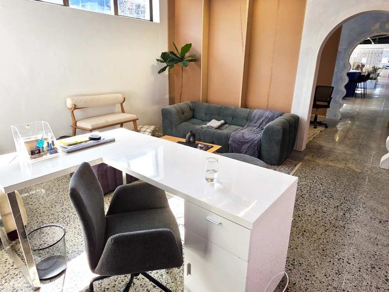 A modern office space featuring polished terrazzo flooring, an architectural arched doorway, and high-level clerestory windows providing natural light.