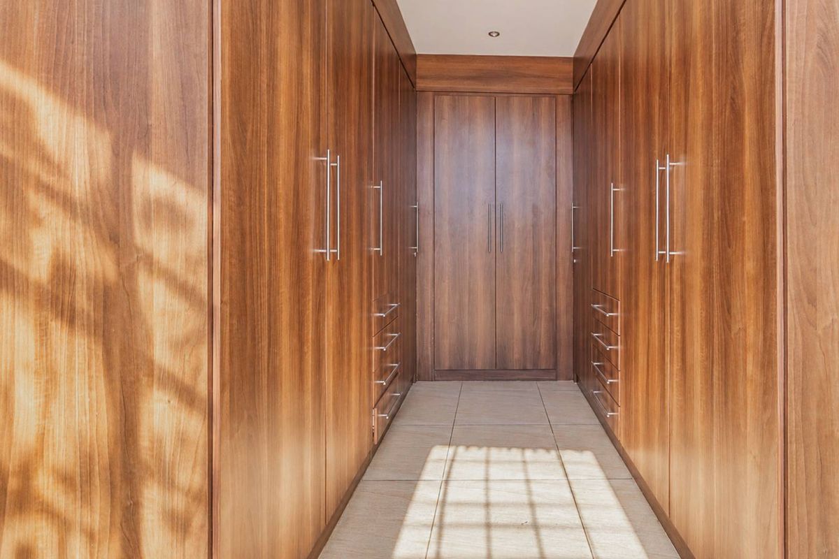 A well-appointed walk-in closet featuring extensive floor-to-ceiling custom wood cabinetry with integrated drawers and sleek metal hardware.