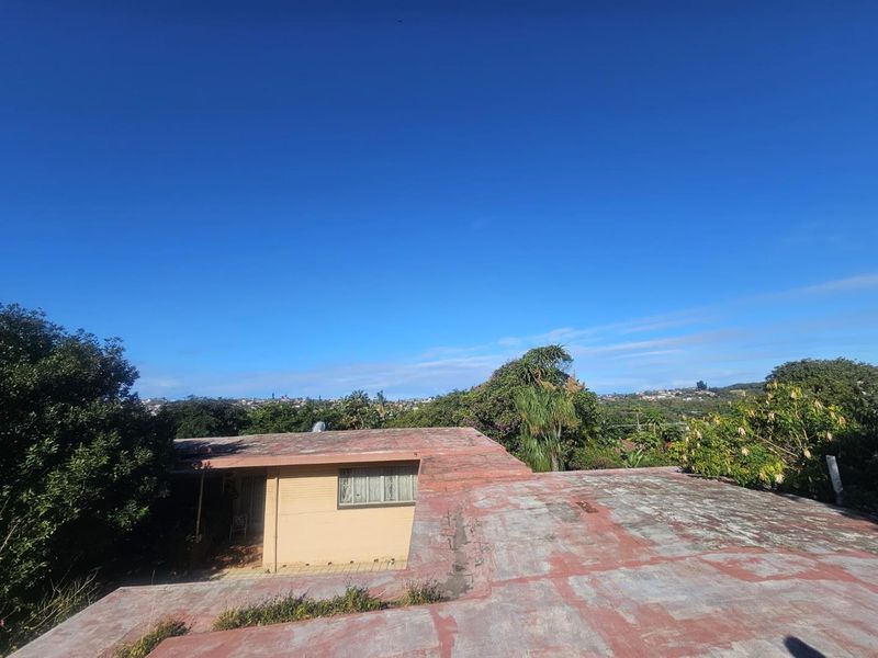 An elevated view of the rear of the property showing the flat roof structure and surrounding garden area.