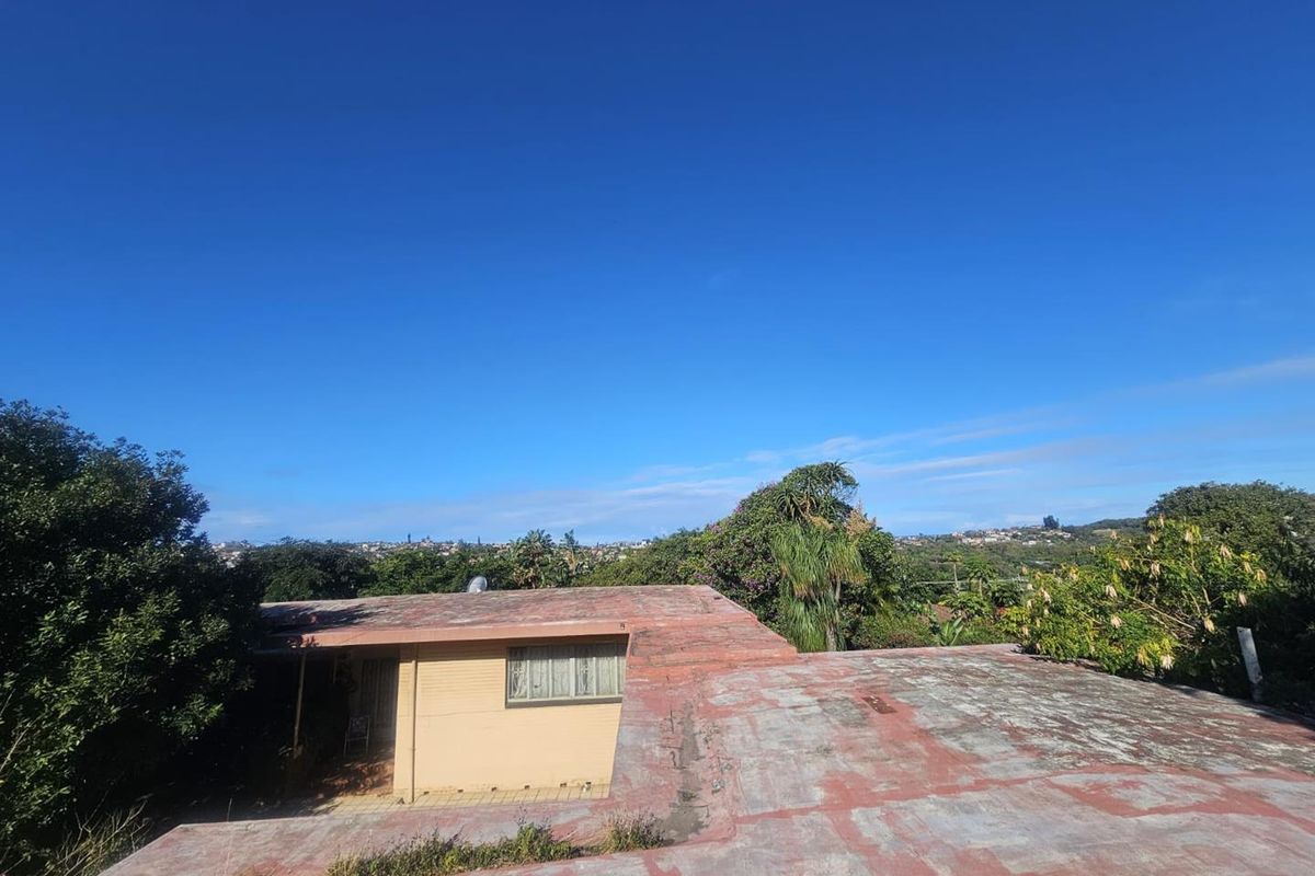 An elevated view of the rear of the property showing the flat roof structure and surrounding garden area.