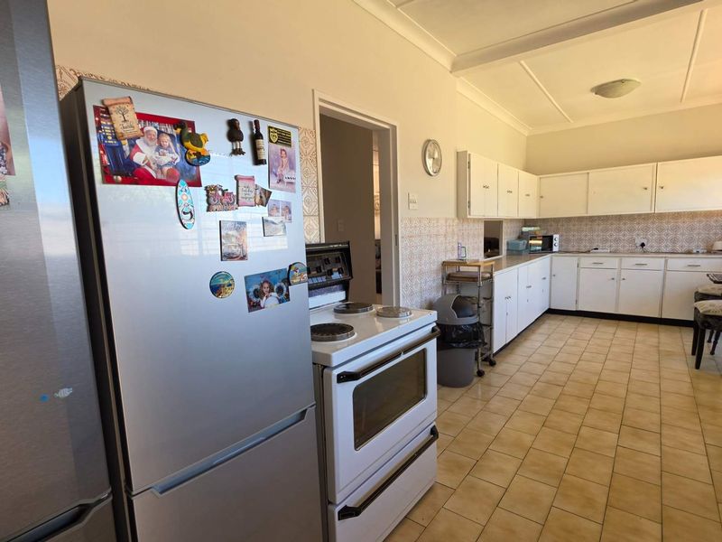 A functional kitchen featuring ample built-in cabinetry, tiled backsplash, and tiled flooring, offering a classic layout ready for modern updates.