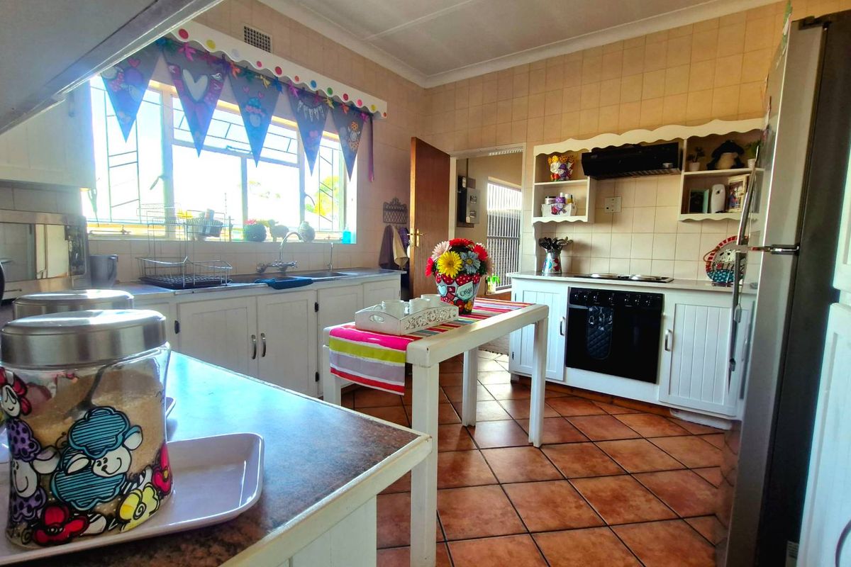 A functional kitchen featuring white cabinetry, tiled backsplash, built-in oven with extractor fan, and terracotta-style floor tiles.