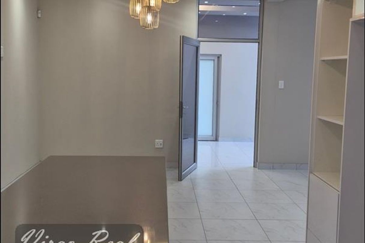 Modern kitchen area featuring sleek stone countertops, built-in cabinetry, and elegant recessed ceiling lighting with a contemporary pendant fixture.