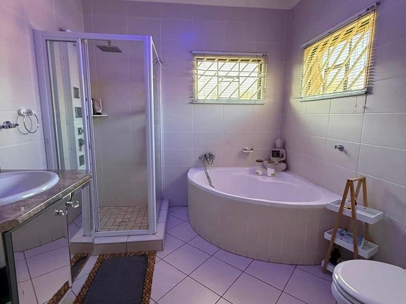 A functional bathroom featuring a corner bathtub, separate shower enclosure, vanity cabinet, and tiled finishes throughout.