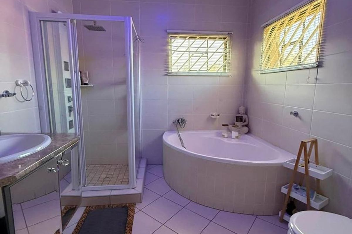 A functional bathroom featuring a corner bathtub, separate shower enclosure, vanity cabinet, and tiled finishes throughout.