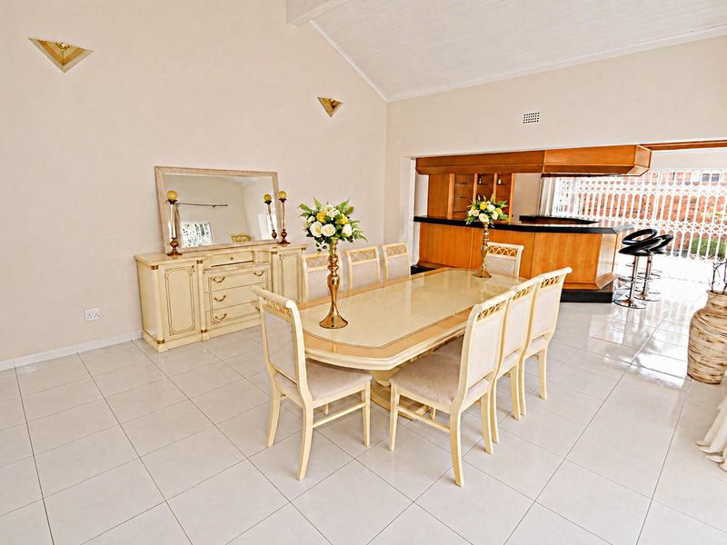 Spacious open-plan dining area featuring tiled flooring, vaulted ceilings, and a built-in bar counter, creating a functional space for entertaining.