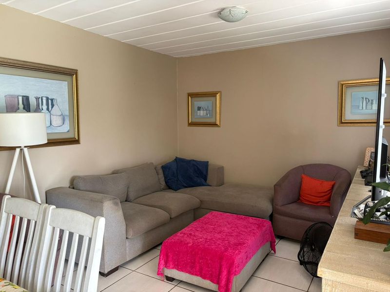 A comfortable living room featuring tiled flooring and a classic tongue and groove ceiling, providing a functional and neutral space.