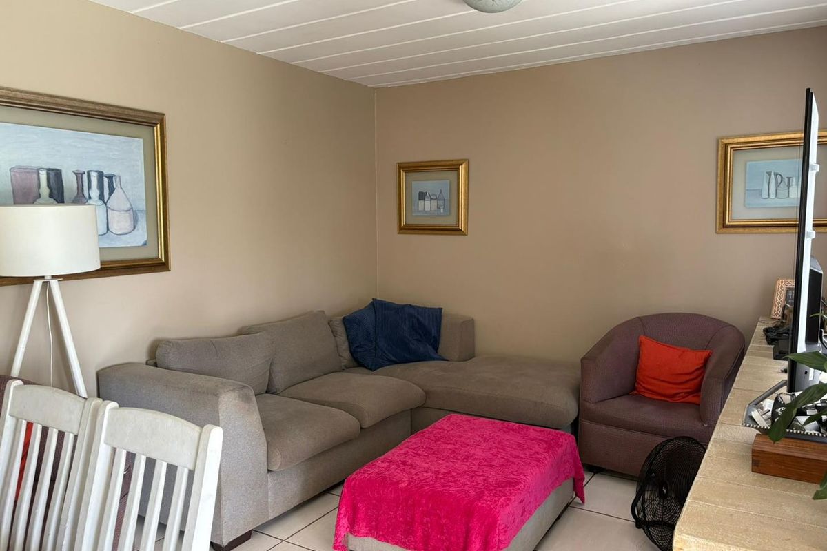 A comfortable living room featuring tiled flooring and a classic tongue and groove ceiling, providing a functional and neutral space.