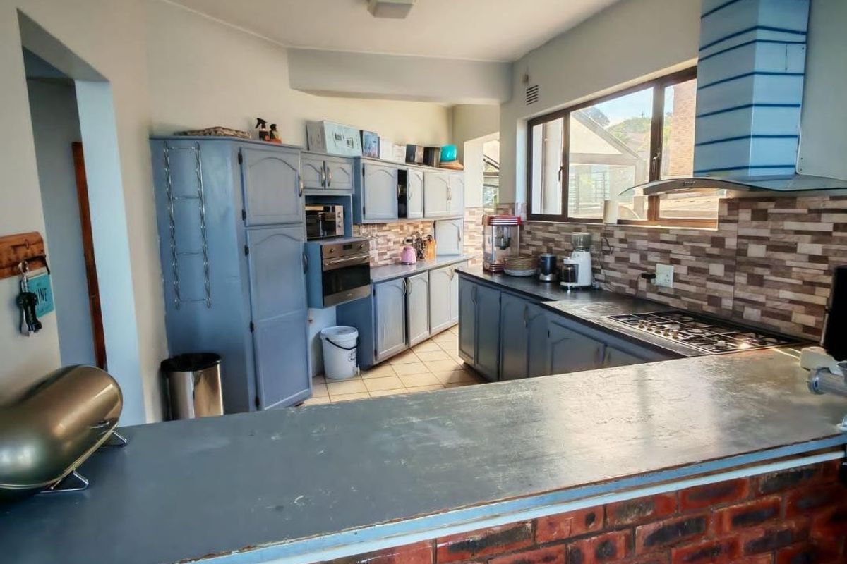 A functional kitchen featuring built-in cabinetry, a gas hob with extractor fan, tiled backsplash, and a brick-faced breakfast bar.