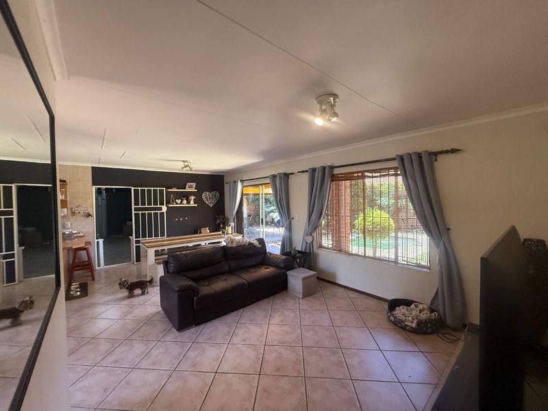 Spacious open-plan living area featuring tiled flooring, large windows with natural light, and direct access to the outdoor patio area.