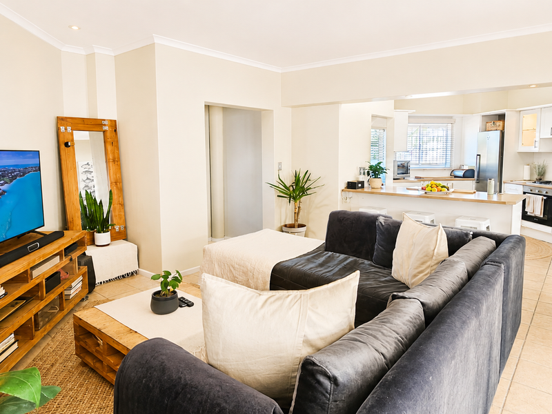 Spacious open-plan living area featuring a modern kitchen with island, built-in appliances, and neutral tiled flooring throughout.