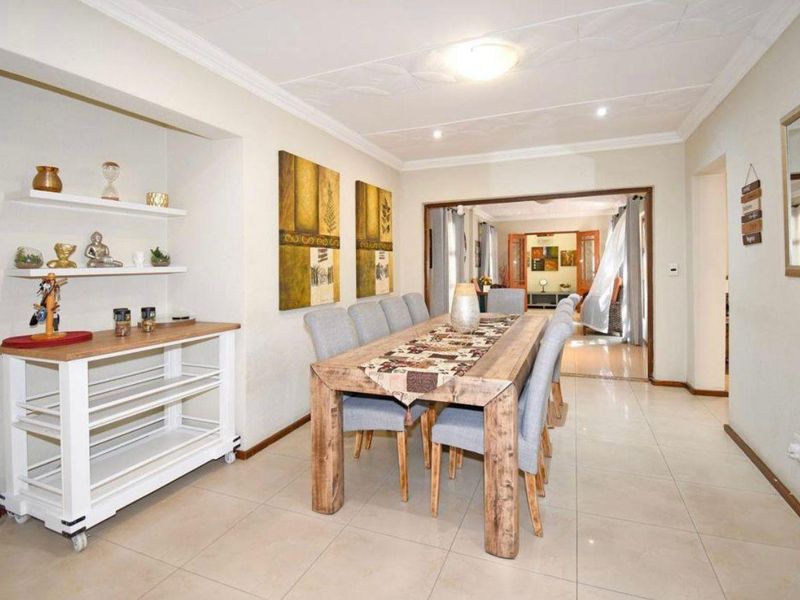A well-lit dining room featuring tiled flooring, coved ceilings, and built-in shelving, providing a functional space for family meals and entertaining.