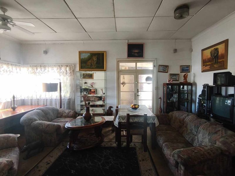 A spacious living room featuring a ceiling fan, tiled ceiling, and a glass panel door leading to the exterior.