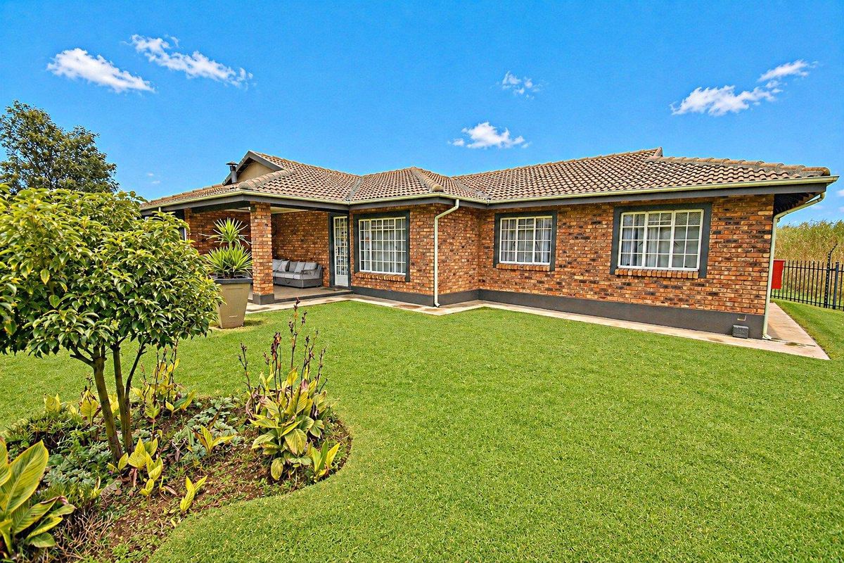A well-maintained brick townhouse featuring a covered patio area, tiled roof, and a neat, landscaped garden.