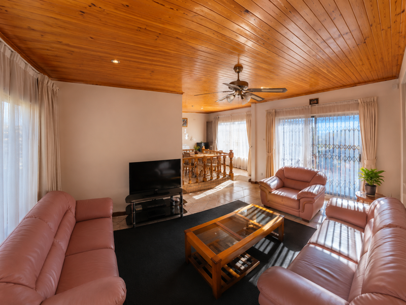 Open-plan living and dining area featuring a warm timber-clad ceiling, ceiling fan, tiled flooring, and sliding glass doors leading to an outdoor space.