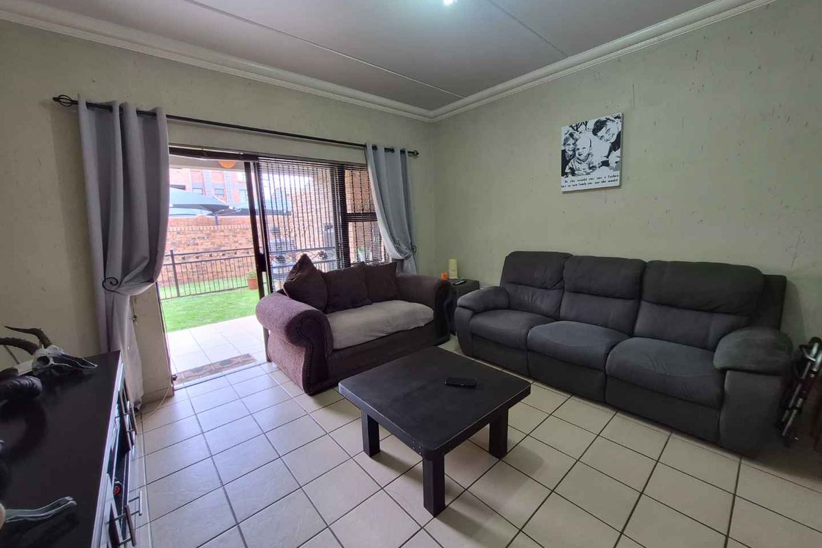 A living room featuring tiled flooring and a sliding glass door providing direct access to an outdoor patio and garden area.