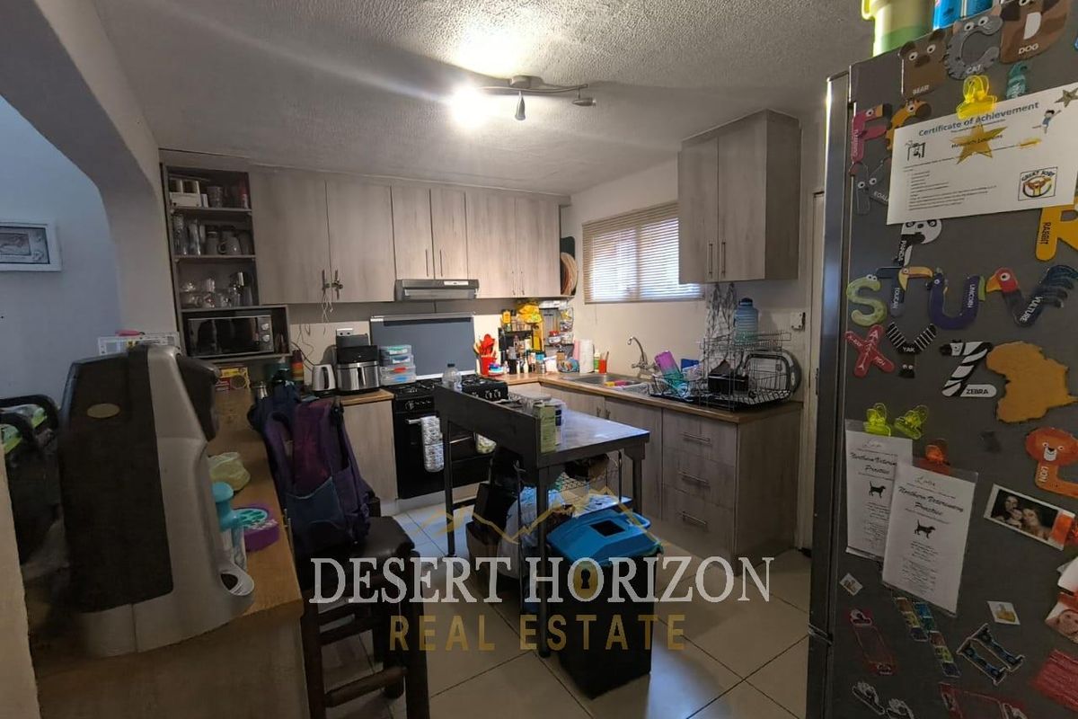 Functional kitchen featuring light wood-tone cabinetry, integrated stove and extractor fan, tiled flooring, and a practical layout with ample counter space.