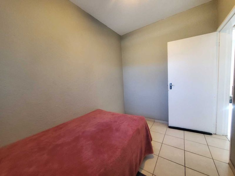 A simple bedroom featuring neutral wall finishes and tiled flooring, providing a functional and clean space.